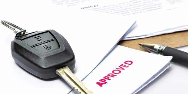 Car keys laying on top of an approved loan application