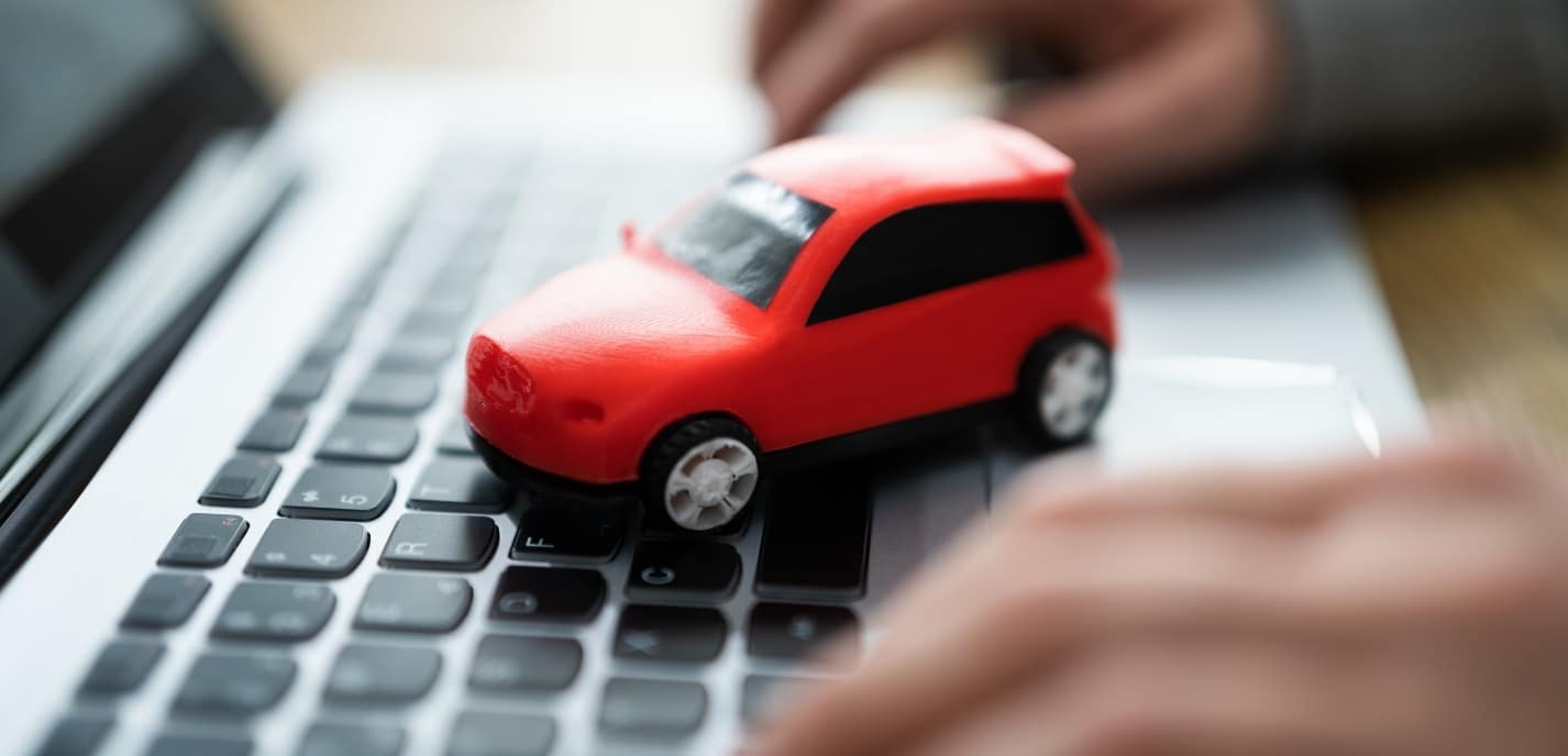 Small toy car on top of a laptop computer keyboard