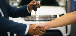 Handshake of two businessmen when selling a car in a dealership