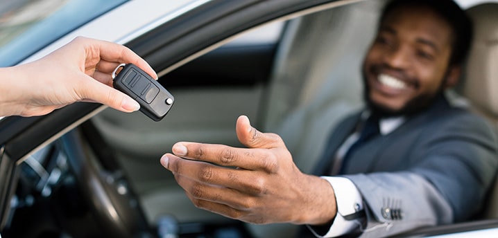 Man smiling while being handed keys to his new car