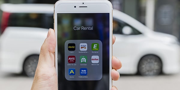 Cell phone with car rental apps in a folder on the screen