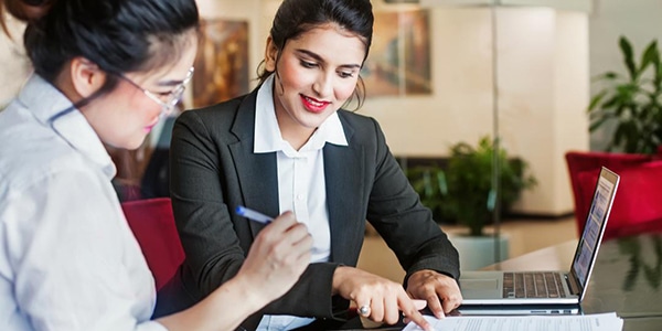 Professional woman helping another woman fill out paperwork