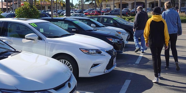 family looking at used cars outside at a dealership