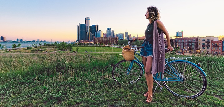 Woman next to a bicycle looking toward the Detroit Michigan skyline