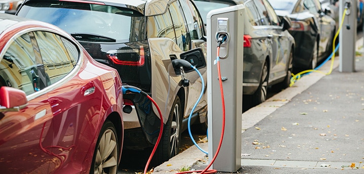 Electric cars lined up on a street while charging