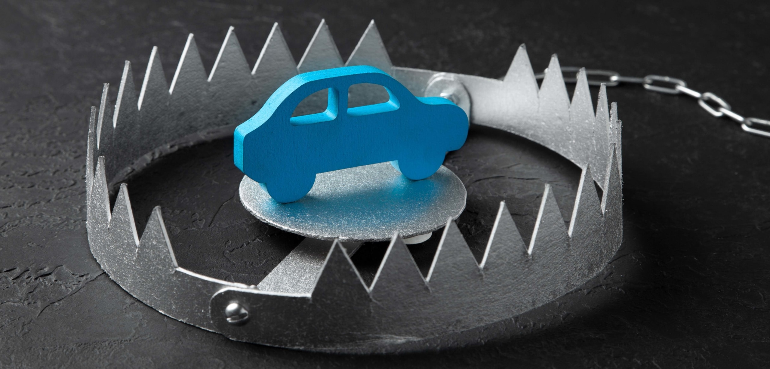 A blue toy car is in the center of a steel trap | 6 Signs You Have a Bad Car Loan