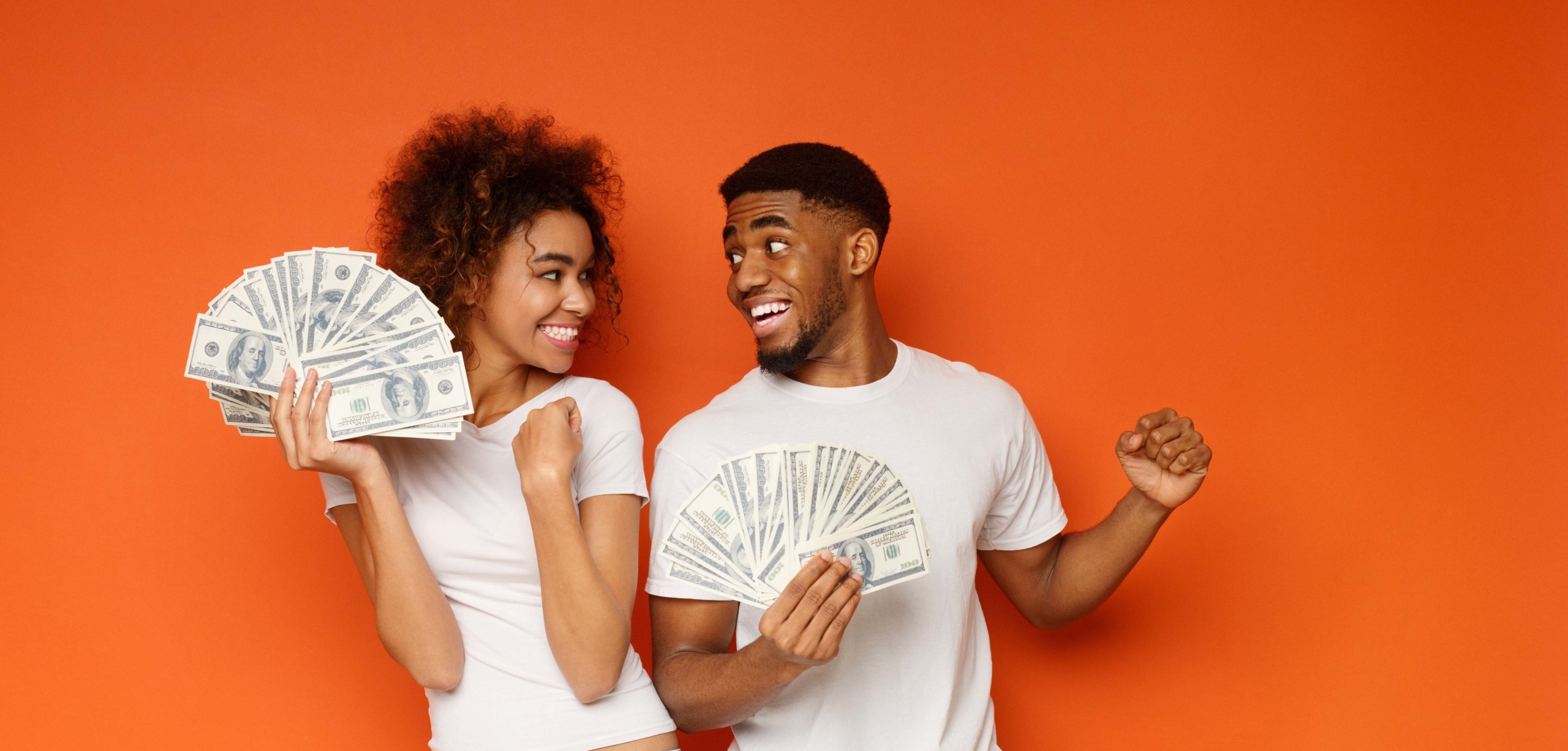 Young Black man and woman are holding a handful of cash and looking excitedly at each other | Should You Combine Expenses After Marriage?