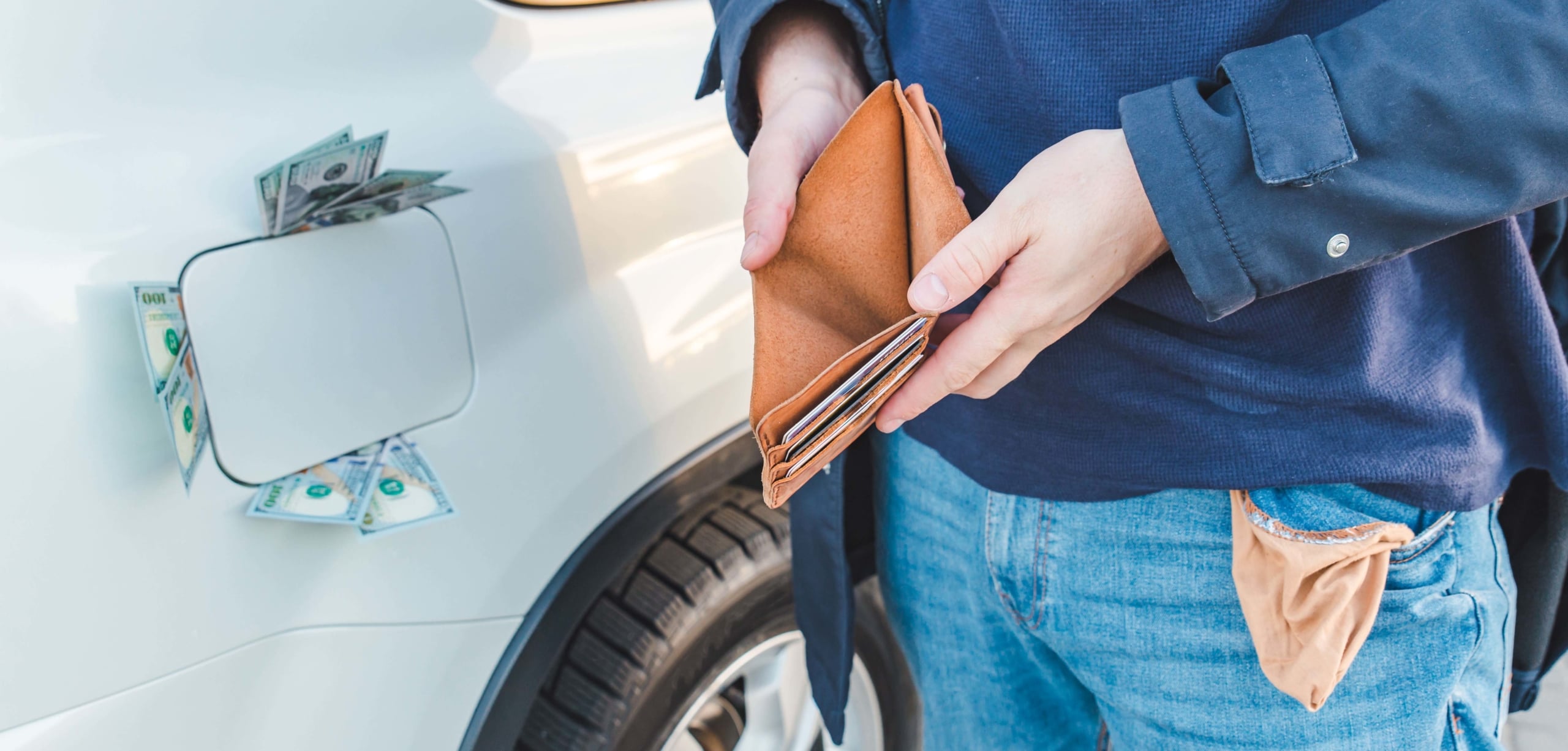 Close up photo of a man holding open an empty wallet next to a gas tank with hundred dollar bills sticking out | 11 Tips to Save Money on Gas Despite Rising Prices