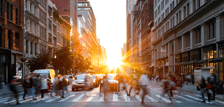 People walking across a busy street during sunrise in Manhattan, New York City |Cities With the Best and Worst Interest Rates