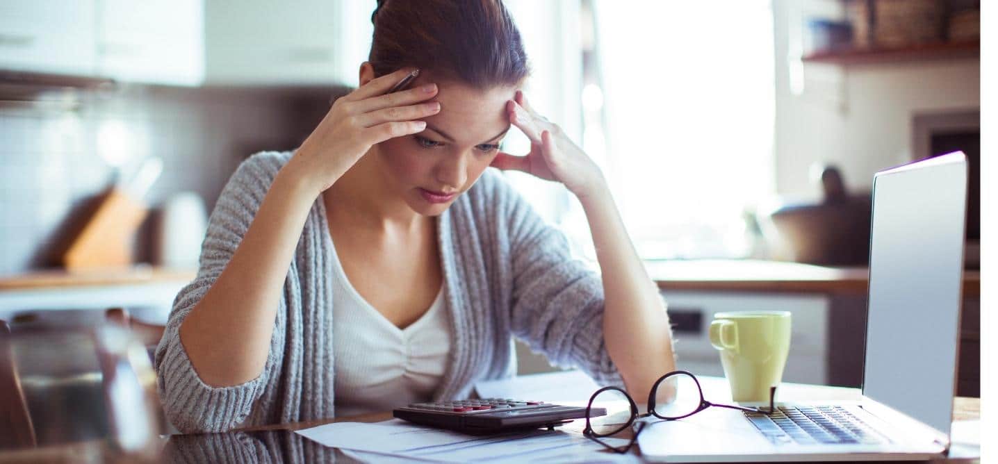 Woman paying bills and looking discouraged looking down at her calculator