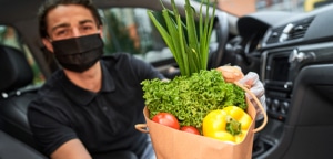 Man sitting in a car holding a bag of fresh produce to be delivered