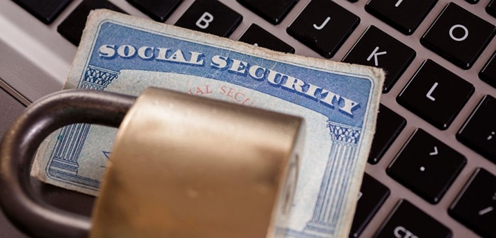 lock with social security card on top of a computer to indicate identity theft