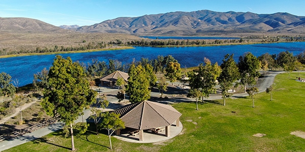 Aerial view of little park in front of Otay Lake City Reservoir with blue sky and mountain in the background, Chula Vista, California