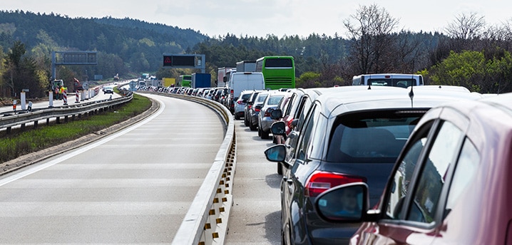 Traffic jam of cars on a highway with mountains and trees in the background