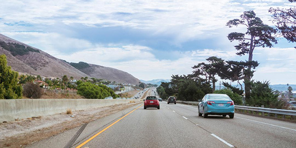 Cars traveling on a highway with mountain ranges in the background in California