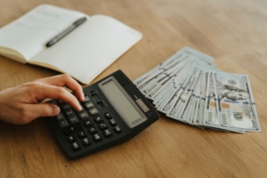 Calculator, note pad and cash on desk.