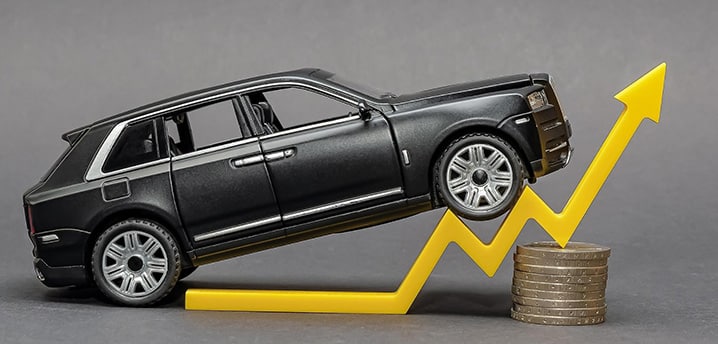 car on top of an upward pointing arrow, sitting on coins to show car prices rising