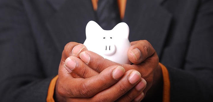 close-up of a man holding a small piggy bank