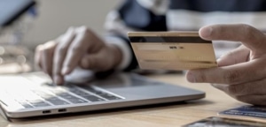 close-up of man using credit card to pay bill on computer