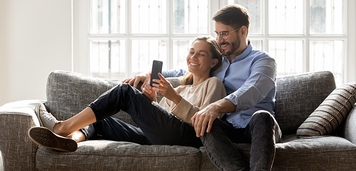 couple on couch comparing car loans on phone