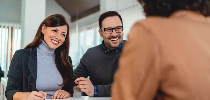 couple smiling while signing a document