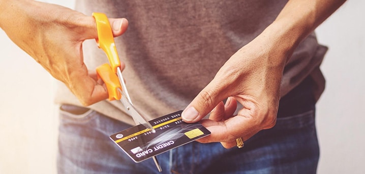 man using scissors to cut a credit card in half