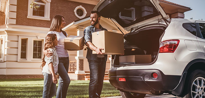 family unpacks vehicle after buying new house