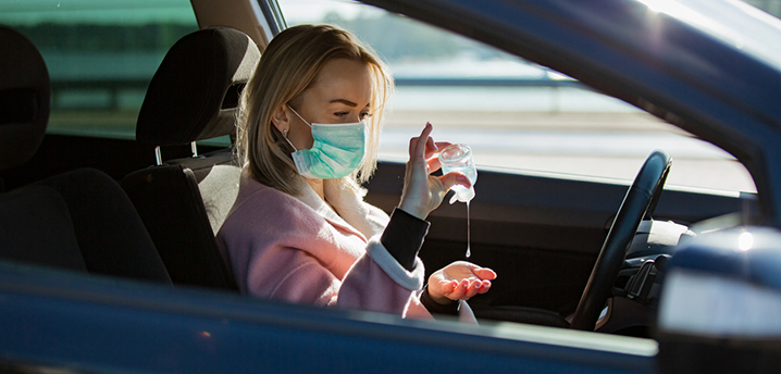 woman disinfecting hands in car covid-19