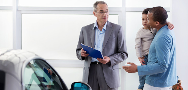 salesman explaining buying vs leasing car to father and son