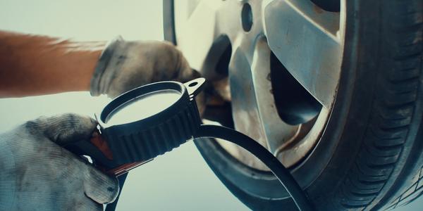 close-up of someone checking the tire pressure on car tires