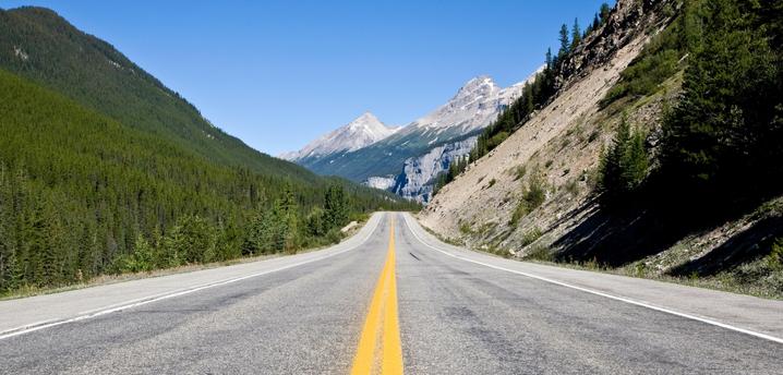 long empty highway heading toward a mountain range