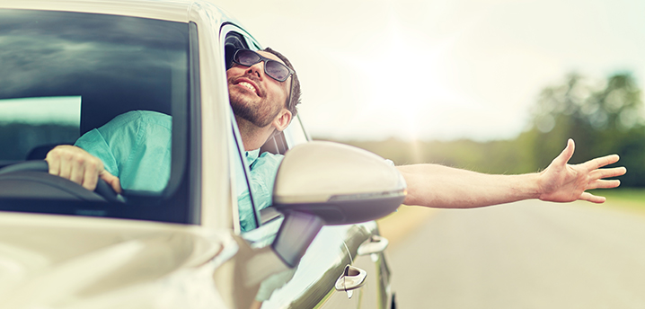man waving arm outside car happy about his good car loan