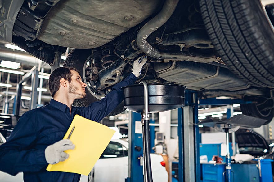 Mechanic looking underneath and inspecting a car