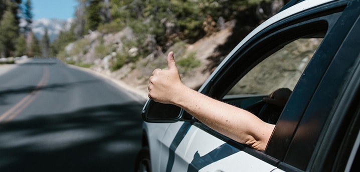 person giving a thumbs up outside of a car window