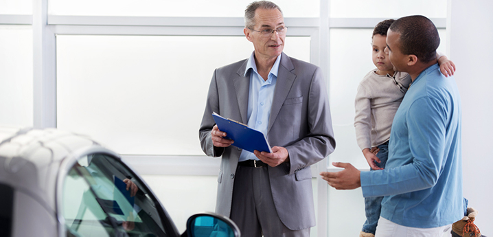 salesman and customer discussing car loan terms at dealership