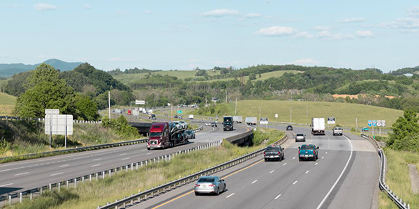 aerial view of cars and trucks driving on a highway with mountains and hills in the background