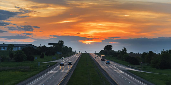 aerial view of cars on a highway with the sun setting in the background