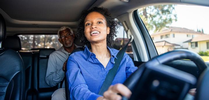 woman driving car for rideshare with a male passenger in the backseat