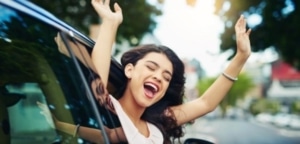 smiling woman leaning out of a car window in her new car
