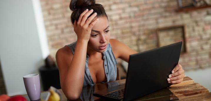 woman seeming frustrated while looking at her computer