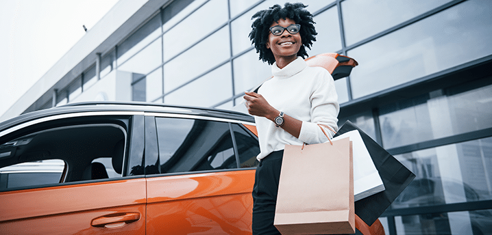 women holding shopping bags in front of her vehicle | how to lower your car payment