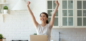 woman at her laptop thrilled she just paid off her car loan